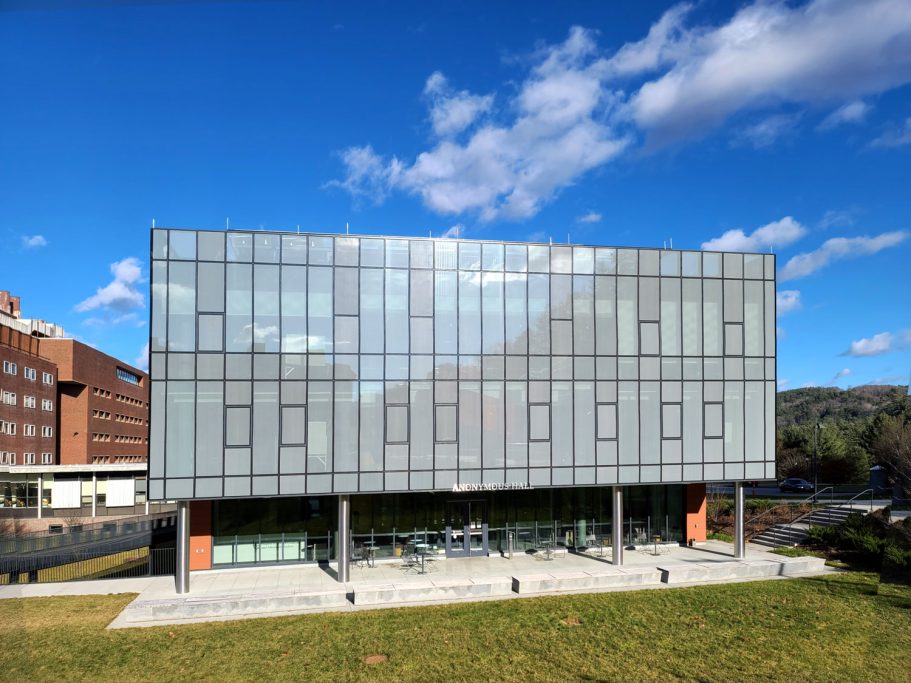 Anonymous Hall, Dartmouth College, US Modern building with glass façade and green landscaping under a blue sky.