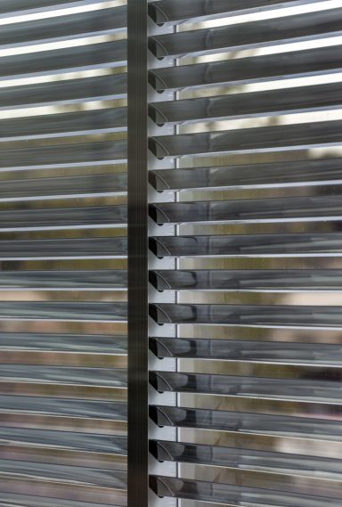 Vertical blinds partially open, revealing a blurred outdoor view.