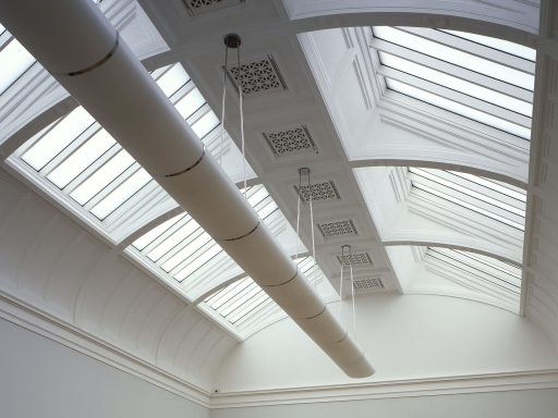 Bright room with a high ceiling, featuring skylights and white walls.
