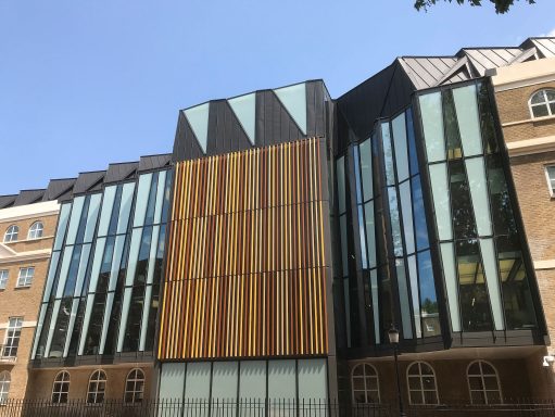 Modern building with glass and wooden panels under a clear blue sky.