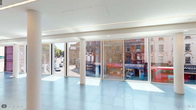 Bright, modern interior space with large windows with metal mesh overlooking a street.