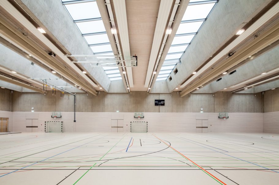 LESC High School Gymnasium, Luxembourg Interior of a sports hall with high ceilings and overhead skylights.