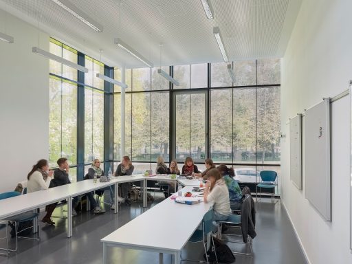 A modern classroom with students engaged in discussion around a bright, spacious table.