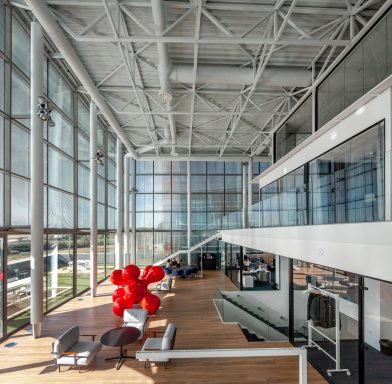 Modern office interior with large windows, wooden floors, and a red sculpture.