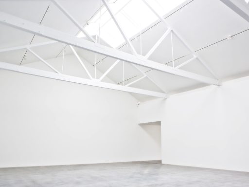 Spacious, well-lit room with white walls and exposed beams.