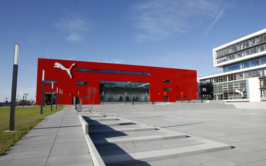 Puma HQ, Herzogenaurach, Germany A modern red building with large windows and a grey paved area in front.