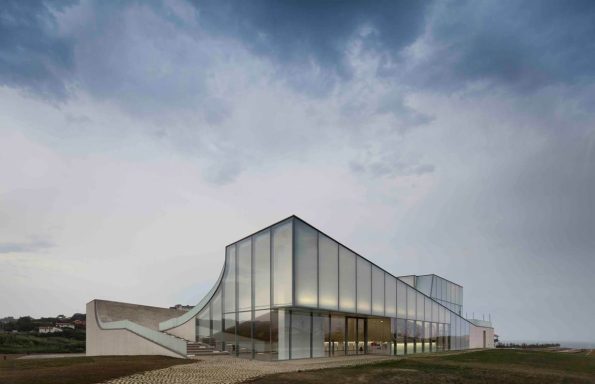 Modern architectural building with a glass facade against a cloudy sky.