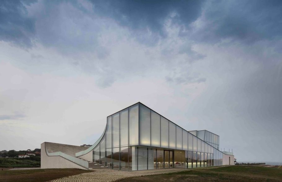 Cité de l’Océan, Biarritz Modern architectural building with glass facade under a cloudy sky.